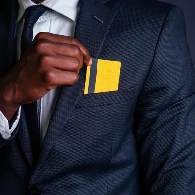  young successful businessman man in a stylish black classic suit and in cool glasses holding a yellow plastic credit card in the studio on a dark background. shopping conceptIndexador: yurakrasil.ruFonte: 223509927<!-- NICAID(14408682) -->