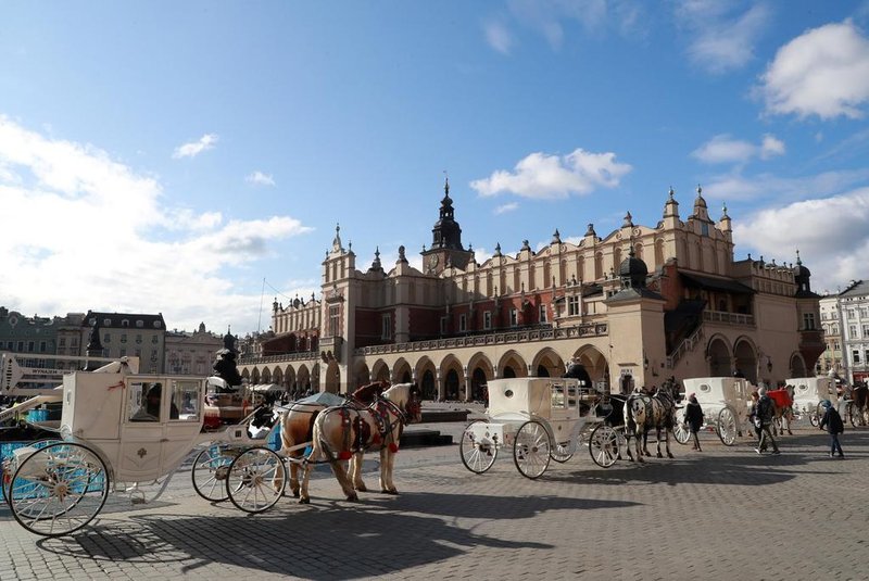 Horse carriages stand near the Cloth Hall building in the old city center in Krakow on Febuary 5, 2020. (Photo by Ludovic MARIN / AFP)<!-- NICAID(14410423) -->