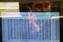 A stockbroker wearing a facemask amid concerns over the spread of the COVID-19 novel coronavirus, watches the share prices during a trading session at the Pakistan Stock Exchange (PSX) in Karachi on March 16, 2020. (Photo by Asif HASSAN / AFP)<!-- NICAID(14452534) -->
