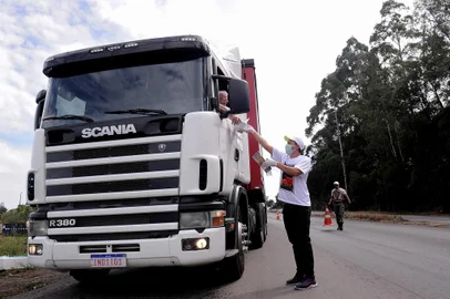  CAXIAS DO SUL, RS, BRASIL, 28/03/2020 - Protegidos com luvas e náscaras, grupo de voluntários distribuem marmitas aos caminhoneiros, que enfrentam dificuldades para se alimentar, com decreto que não permite abertura de restaurantes. A ação ocorreu na Rota do Sol, próximo ao viaduto torto, e contou com apoio da Brigada Militar. (Marcelo Casagrande/Agência RBS)<!-- NICAID(14463799) -->