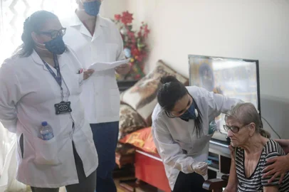  PORTO ALEGRE, RS, BRASIL - 2020.04.01 - Vacinação de gripe a domicílio para idosos. Pessoas com mais de 80 anos que já acessaram unidades de saúde da Secretaria Municipal de Saúde (SMS) são vacinadas contra a influenza em casa a partir desta quarta-feira, 1º de abril. Na imagem: Apartamento de Paulo Martins, 83 e Garcinda Vieira Martins, 87. Cuidadora que também tomou vacina, Karina Grassi dos Santos. (Foto: André Ávila/Agencia RBS)Indexador: Andre Avila<!-- NICAID(14466701) -->