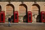 A woman passes red telephone boxes as she walks in the spring sunshine on the coast in Blackpool, north-west England on April 13, 2020, during the nationwide lockdown to combat the novel coronavirus pandemic. - The death toll in Britain from coronavirus has risen to 11,329, according to health ministry figures published Monday -- an increase of 717 on the previous days figures. The daily increase is the lowest for several days, although it is not unusual for numbers to drop after a weekend due to delays in collating data. The numbers only refer to deaths in hospital. (Photo by Oli SCARFF / AFP)<!-- NICAID(14476399) -->