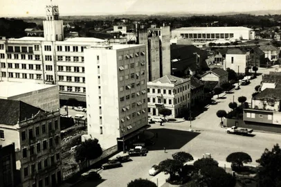 A esquina das ruas Sinimbu e Marquês do Herval sediou, ao longo das décadas, alguns dos estabelecimentos de negócio mais importantes da área central. Entram aí a Casa Minghelli, o Hotel Bela Vista e a Adega Pezzi.Na imagem, o trecho no final dos anos 1960. No final da década de 1960, o complexo da vinícola, que praticamente estendia-se quase até a Rua Os Dezoito do Forte (detalhe ao lado), cedeu espaço a alguns dos primeiros arranha-céus de Caxias, os edifícios Dona Ercília e Marina. Na foto, à direita, vemos os tapumes que então cercavam o terreno do Dona Ercília. Na foto aparecem ainda o Hotel Menegotto, a Metalúrgica Abramo Eberle, o Hotel Bela Vista e a sede da Festa da Uva (hoje prefeitura de Caxias). <!-- NICAID(10692892) -->