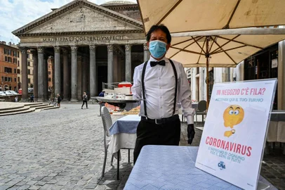 A waiter is pictured at a cafe terrace by the Pantheon monument in central Rome on May 18, 2020 during the countrys lockdown aimed at curbing the spread of the COVID-19 infection, caused by the novel coronavirus. - Restaurants and churches reopen in Italy on May 18, 2020 as part of a fresh wave of lockdown easing in Europe and the countrys latest step in a cautious, gradual return to normality, allowing businesses and churches to reopen after a two-month lockdown. (Photo by ANDREAS SOLARO / AFP)<!-- NICAID(14502429) -->