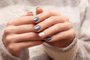 Female hands with blue glitter nail design.Mãos femininas com design de unhas azul brilhanteFonte: 297809703<!-- NICAID(14316722) -->
