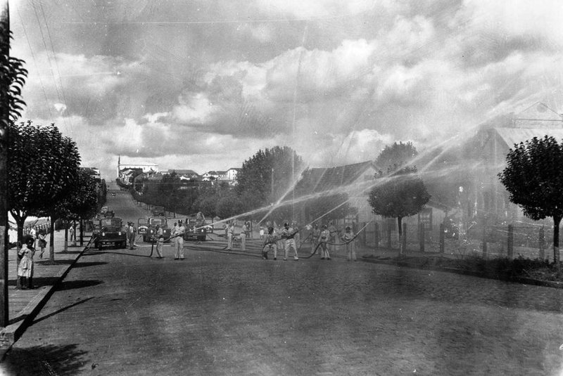 Demonstração de combate ao fogo pelos bombeiros na Rua Sinimbu em direção a Coronel Flores, onde ficava a antiga sede, por volta de 1958. Local é em frente ao Colégio São Carlos<!-- NICAID(14537741) -->