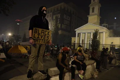 WASHINGTON, DC - JULY 04: An activist stands in smoke as he holds a Black Lives Matter sign at Black Lives Matter Plaza near the White House during the annual Independence Day fireworks show July 4, 2020 in Washington, DC. Anti-Trump activists rallied on Independence Day to voice their disapproval of President Trumps handling in the wake of the death of George Floyd.   Alex Wong/Getty Images/AFP<!-- NICAID(14538330) -->