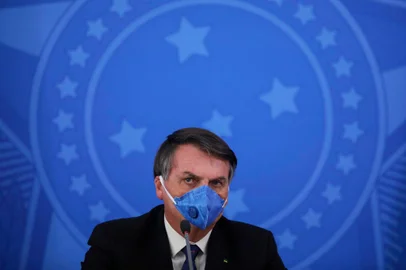 Brazils President Jair Bolsonaro wears a face mask during a press conference on the coronavirus pandemic COVID-19 at the Planalto Palace in Brasilia, Brazil on March 20, 2020. - Brazils government on Friday drastically downgraded its growth projections for 2020 by 2.1 percent to practically zero (0.02 percent) due to the coronavirus pandemic. (Photo by Sergio LIMA / AFP)<!-- NICAID(14461916) -->