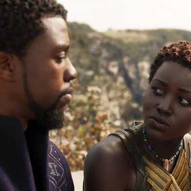 Chadwick Boseman como o personagem Tchalla, protagonista e herói homônimo do filme Pantera Negra. Ao seu lado, Lupita Nyongo, que interpreta Nakia, espiã e guarda pessoal do rei TChalla.