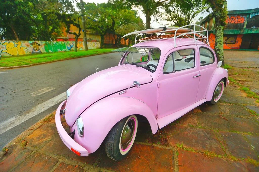 Com prancha no teto e mala retrô sobre o motor, fusca rosa chama a ...