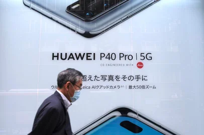 (FILES) In this file photo taken on June 27, 2020 a man walks past an advertisement for the latest smartphone by Chinese telecommunications company Huawei in Tokyo. - Apple is expected on October 13, 2020, to unveil a keenly anticipated iPhone 12 line-up starring models tuned to super-fast new 5G telecom networks in an update considered vital to the companys fortunes. (Photo by Kazuhiro NOGI / AFP) / TO GO WITH AFP STORY JAPAN-CHINA-US-BRITAIN-TELECOMMUNICATION,FOCUS BY ERWAN LUCAS<!-- NICAID(14620986) -->