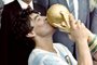 (FILES) In this file picture taken on June 29, 1986 Argentina's football star team captain Diego Maradona kisses the World Soccer Cup won by his team after a 3-2 victory over West Germany at the Azteca stadium in Mexico City watched by Mexican President Miguel de La Madrid (L) and West German Chancellor Helmut Kohl. - Argentine football legend Diego Maradona turns 60 on October 30, 2020. (Photo by STAFF / AFP)<!-- NICAID(14629180) -->