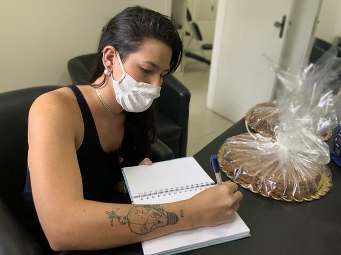 Camila escreve a mão os bilhetes que envia junto