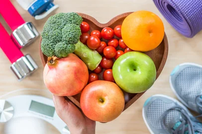 Healthy lifestyle concept, eating clean food good health dietary in heart dish with sporty aerobic body exercise workout training class gym equipment, weight scale and sports shoes in fitness center