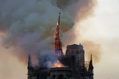The steeple engulfed in flames collapses as the roof of the Notre-Dame de Paris Cathedral burns on April 15, 2019 in Paris. - A colossal fire swept through the famed Notre-Dame Cathedral in central Paris on April 15, 2019, causing a spire to collapse and raising fears over the future of the nearly millenium old building and its precious artworks. The fire, which began in the early evening, sent flames and huge clouds of grey smoke billowing into the Paris sky as stunned Parisians and tourists watched on in sheer horror. (Photo by Geoffroy VAN DER HASSELT / AFP)