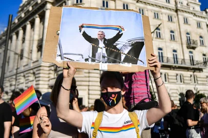 (FILES) In this file photo taken on June 14, 2021 a participant holds a placard showing Hungarian Prime Minister Viktor Orban holding a scarf in rainbow colours, in front of the parliament building in Budapest, during a demonstration against the Hungarian governments draft bill seeking to ban the promotion of homosexuality and sex changes. - Hungarys Prime Minister Viktor Orban said on July 21, 2021 that a referendum would be held to gauge domestic support for a controversial LGBTQ law, after the European Commission launched legal action against Budapest over the measure. (Photo by GERGELY BESENYEI / AFP)<!-- NICAID(14840710) -->