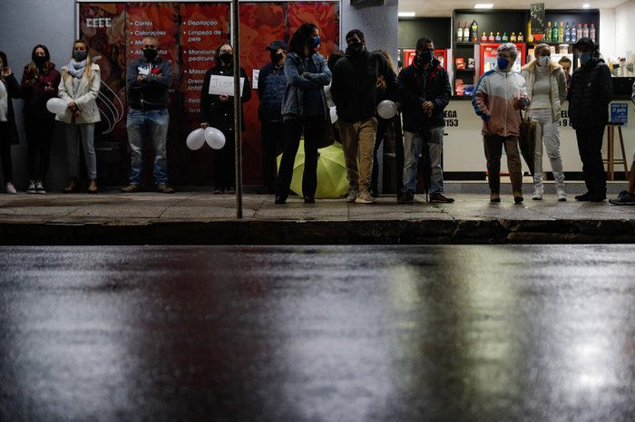 Para se proteger da chuva, algumas pessoas ficaram embaixo de marquises