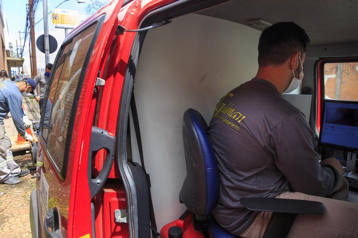 Um funcionário acompanha as imagens em tempo real dentro de um laboratório móvel adaptado em um carro