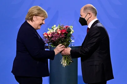 German Chancellor Olaf Scholz gives a bouquet of flowers to his predecessor Angela Merkel after she handed him over the office at the Chancellery in Berlin on December 8, 2021. - Members of the parliament elected Olaf Scholz as the countrys next Chancellor, ushering in a new political era with the centre-left in charge. Together with the Greens and the liberal Free Democrats, Scholzs SPD managed in a far shorter time than expected to forge a coalition that aspires to make Germany greener and fairer. (Photo by John MACDOUGALL / AFP)<!-- NICAID(14962684) -->