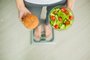 Dieting concept, beautiful young woman choosing between healthy food and junk foodPORTO ALEGRE, RS, BRASIL, dieta, vida saudavel, salada, (Foto: Maksymiv Iurii  / stock.adobe.com)Fonte: 274880218<!-- NICAID(14329111) -->