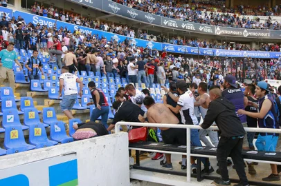 Supporters of Atlas fight with supporters of Queretaro during the Mexican Clausura tournament football match between Queretaro and Atlas at Corregidora stadium in Queretaro, Mexico on March 5, 2022. - A match between Mexican football clubs was called off March 5, 2022 after violence by opposing fans spilled onto the field. The game between Queretaro and Atlas at La Corregidora stadium in the city of Queretaro  -- the ninth round of the 2022 Clausura football tournament -- was in its 63rd minute when fights between opposing fans broke out. (Photo by EDUARDO GOMEZ / AFP)Editoria: SPOLocal: QuerétaroIndexador: EDUARDO GOMEZSecao: soccerFonte: AFPFotógrafo: STR<!-- NICAID(15034273) -->