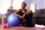 Senior Black woman sitting on floor with exercise equipmentFonte: 72390857<!-- NICAID(15046894) -->