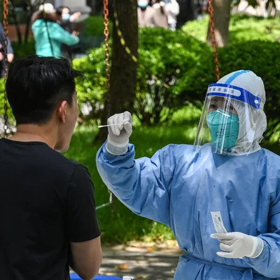 A health worker conducts a swab test for the Covid-19 coronavirus at a residential compound during the second stage of a pandemic lockdown in Jing an district in Shanghai on April 6, 2022. (Photo by HECTOR RETAMAL / AFP)<!-- NICAID(15064721) -->