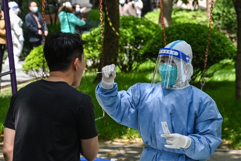 A health worker conducts a swab test for the Covid-19 coronavirus at a residential compound during the second stage of a pandemic lockdown in Jing an district in Shanghai on April 6, 2022. (Photo by HECTOR RETAMAL / AFP)<!-- NICAID(15064721) -->