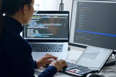 Young Asian woman, developer programmer, software engineer, IT support, wearing glasses working on computer to check coding in bugging system. Back viewFonte: 500709335<!-- NICAID(15185742) -->
