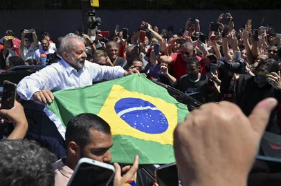 Brazilian former President (2003-2010) and candidate for the leftist Workers Party (PT) Luiz Inacio Lula da Silva unfolds a Brazilian flag while leaving the polling station during the presidential run-off election, in Sao Paulo, Brazil, on October 30, 2022. - After a bitterly divisive campaign and inconclusive first-round vote, Brazil elects its next president in a cliffhanger runoff between far-right incumbent Jair Bolsonaro and veteran leftist Luiz Inacio Lula da Silva. (Photo by NELSON ALMEIDA / AFP)Editoria: POLLocal: Sao PauloIndexador: NELSON ALMEIDASecao: electionFonte: AFPFotógrafo: STF<!-- NICAID(15249961) -->