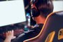 Rear view of a male cybersport gamer wearing headphones playing online video games while sitting in gaming club or in internet cafeAtleta de e-sports - Foto: Friends Stock/stock.adobe.comFonte: 381750068<!-- NICAID(15321099) -->