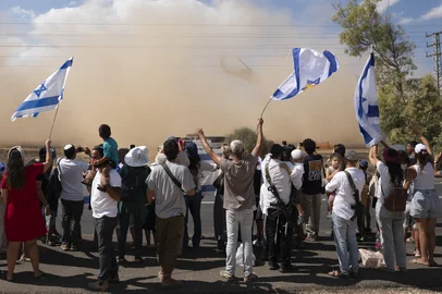 Israelis gather with national flags outside the Reim military base near the border with Gaza in southern Israel on October 13, 2025 to welcome the hostages about to arrive following their release by Hamas from the Gaza Strip. The Palestinian militant group was set to release all surviving Israeli hostages on October 13 in exchange for Palestinian prisoners held by Israel, as US President Donald Trump headed to the region for a peace summit having declared the war "over". Trump's lightning visit to Israel and Egypt aims to celebrate his role in brokering last week's ceasefire and hostage release deal -- but comes at a precarious time as Israel and Hamas negotiate what comes next. (Photo by Maya LEVIN / AFP)Editoria: WARLocal: Re'imIndexador: MAYA LEVINSecao: armed conflictFonte: AFPFotógrafo: STR<!-- NICAID(16144662) -->